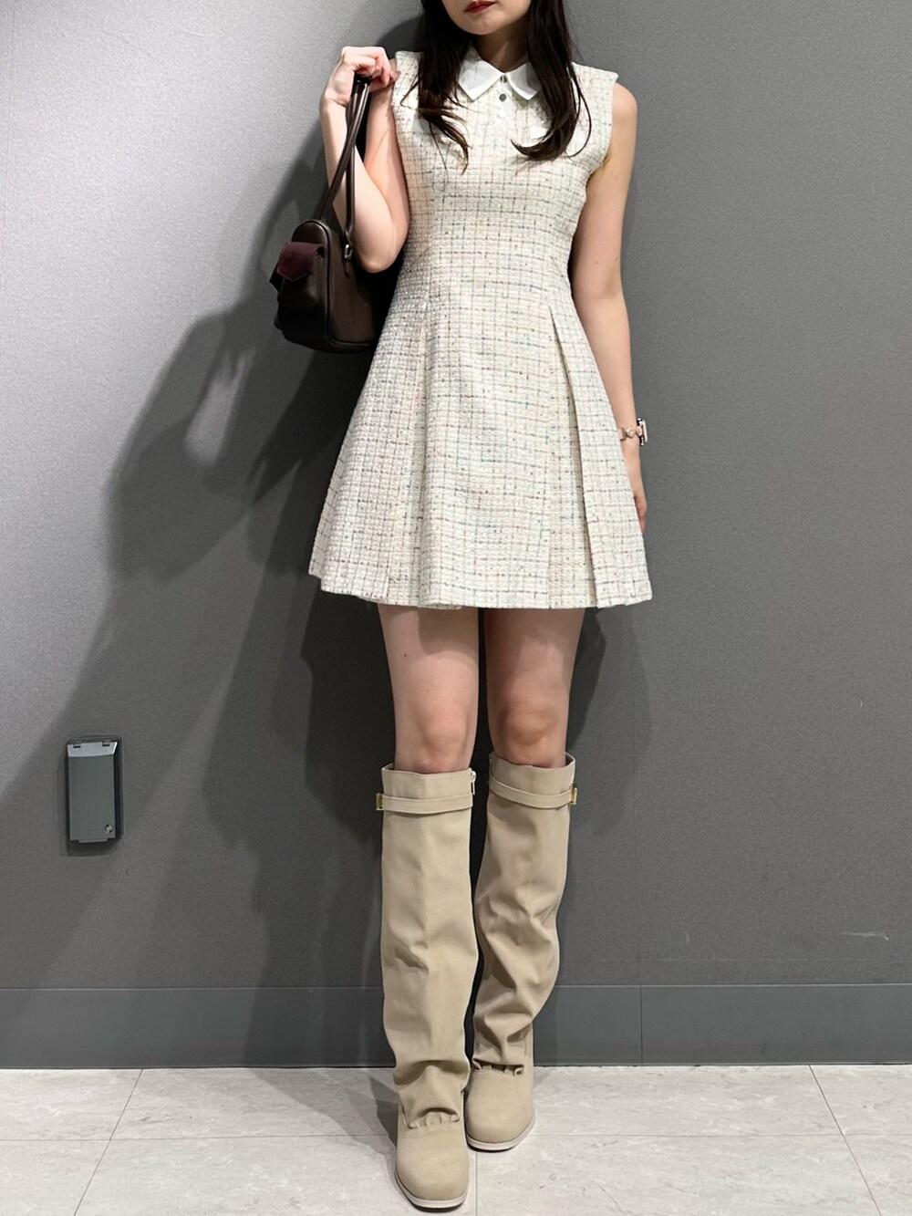 ホワイト系のワンピース、ブラウン系のボストンバッグ、ホワイト系のブーツを着用したレディースの夏コーディネートの2枚目の写真