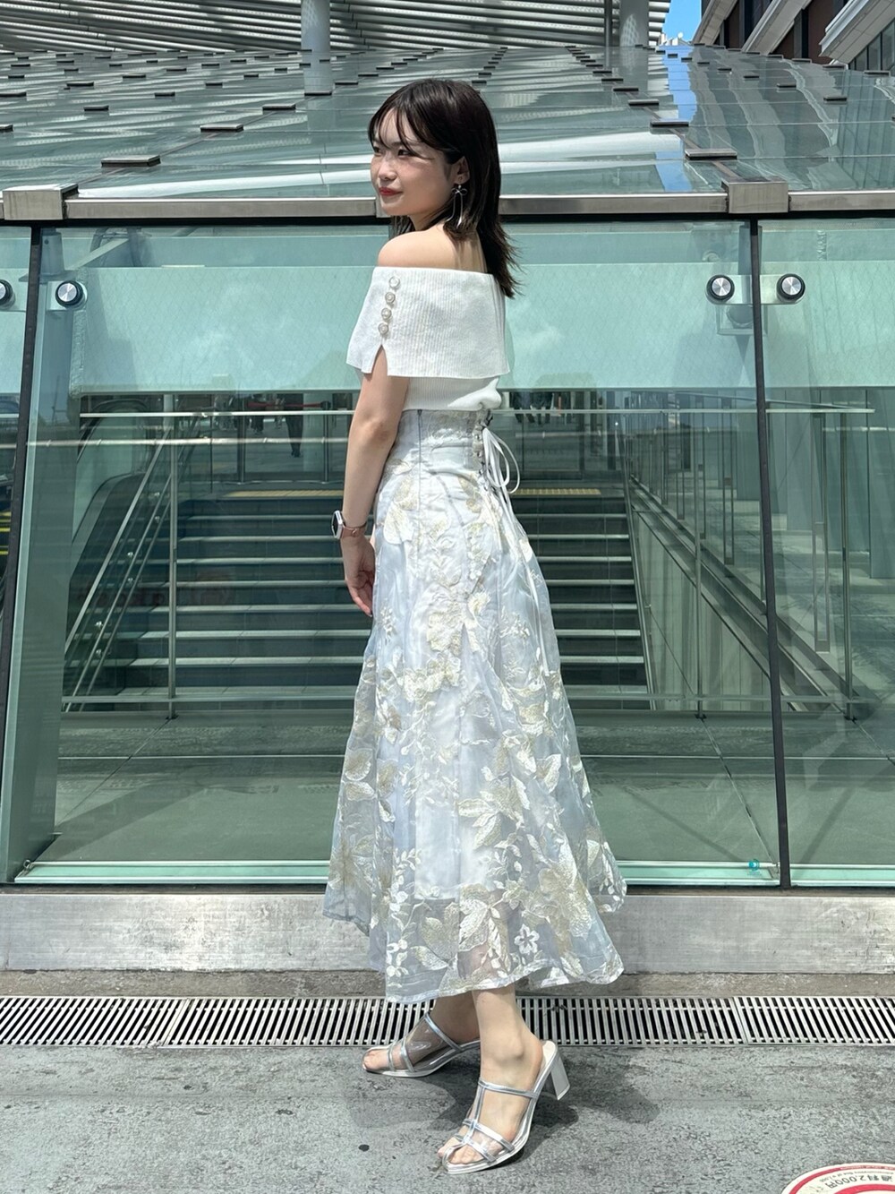 グレー系のスカート、グレー系のニット/セーター、シルバー系のパンプスを着用したレディースの夏コーディネートの3枚目の写真