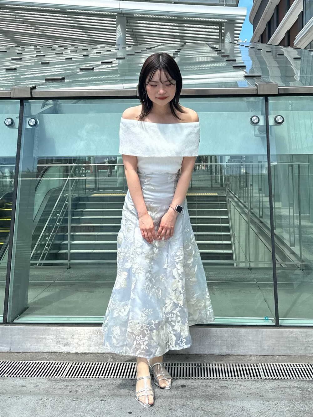 グレー系のスカート、グレー系のニット/セーター、シルバー系のパンプスを着用したレディースの夏コーディネートの2枚目の写真