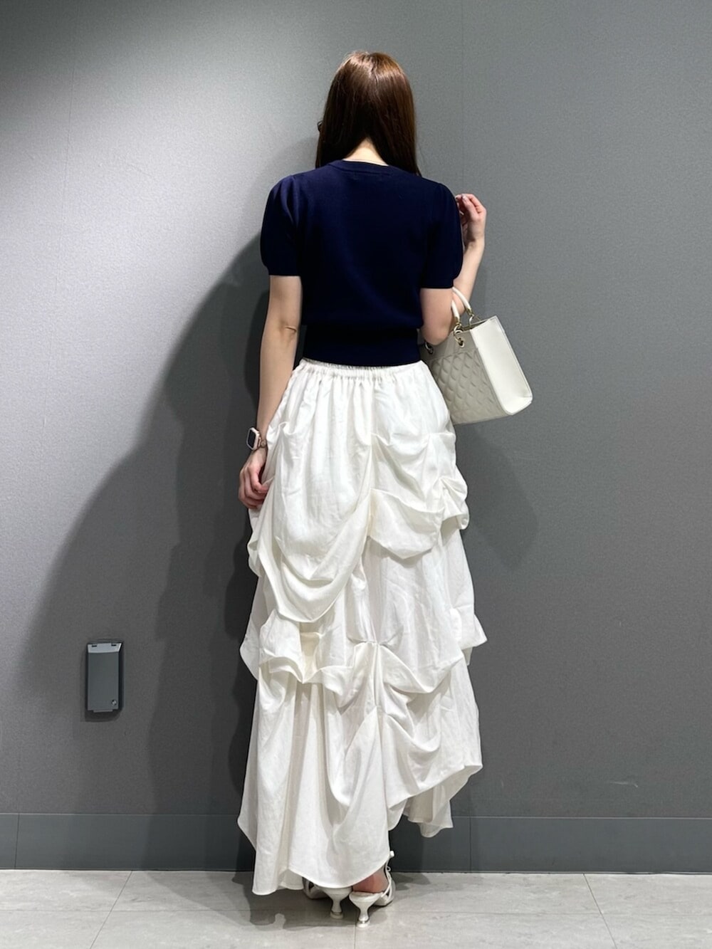 ホワイト系のパンプス、ブルー系のニット/セーター、ホワイト系のスカートを着用したレディースの春コーディネートの8枚目の写真