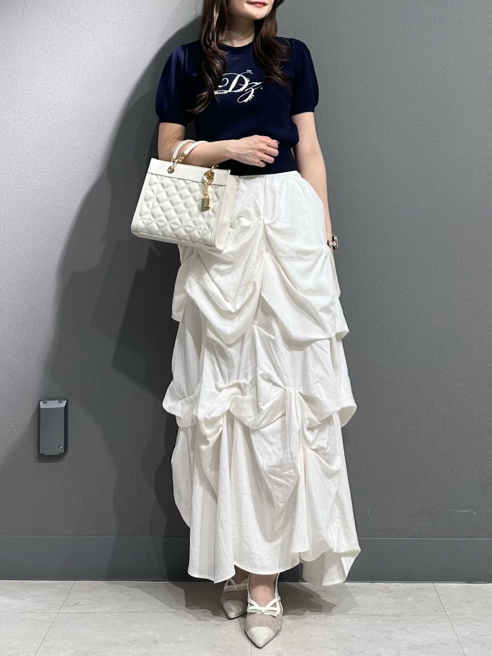 ホワイト系のパンプス、ブルー系のニット/セーター、ホワイト系のスカートを着用したレディースの春コーディネートの3枚目の写真