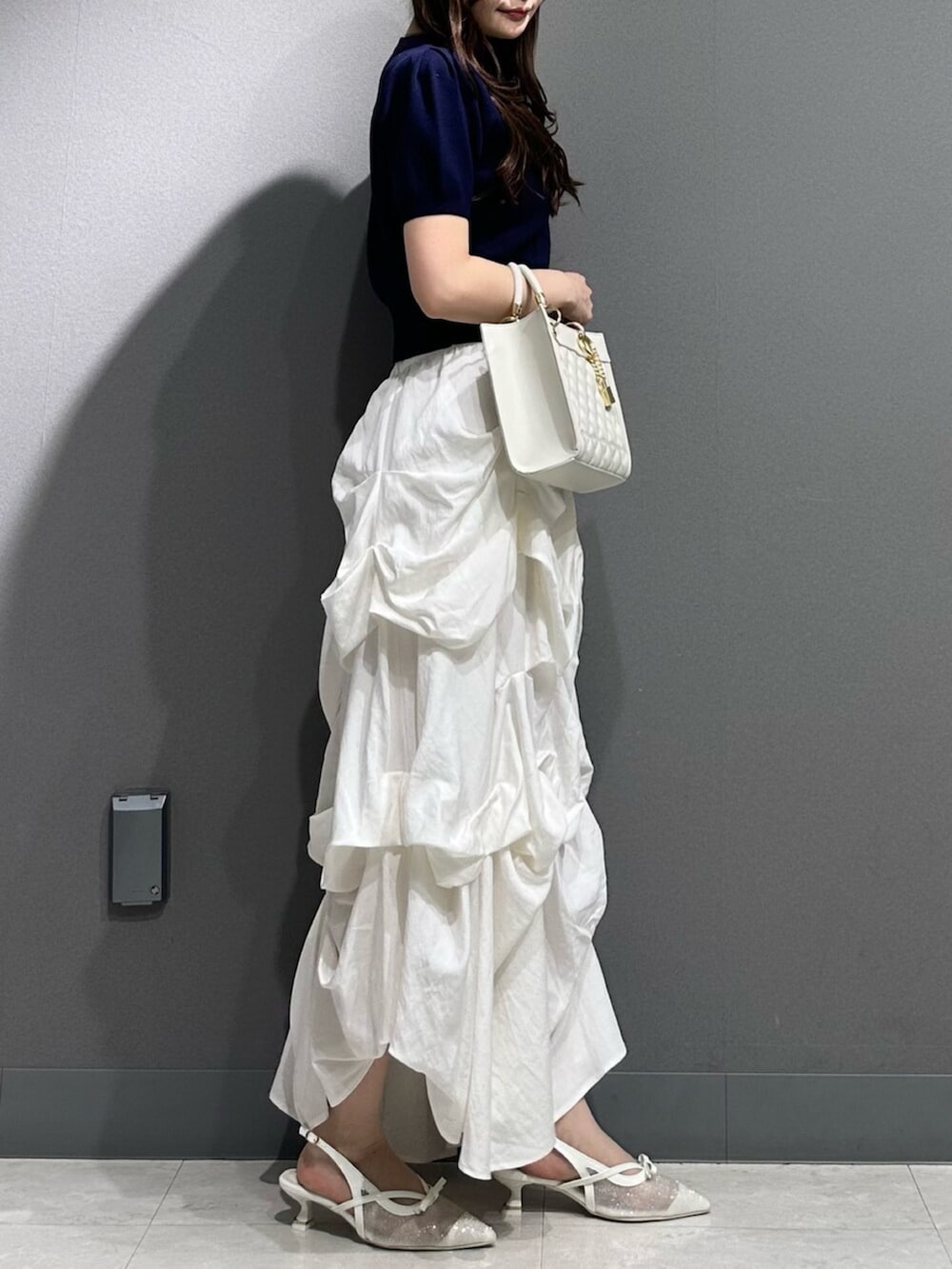 ホワイト系のパンプス、ブルー系のニット/セーター、ホワイト系のスカートを着用したレディースの春コーディネートの7枚目の写真