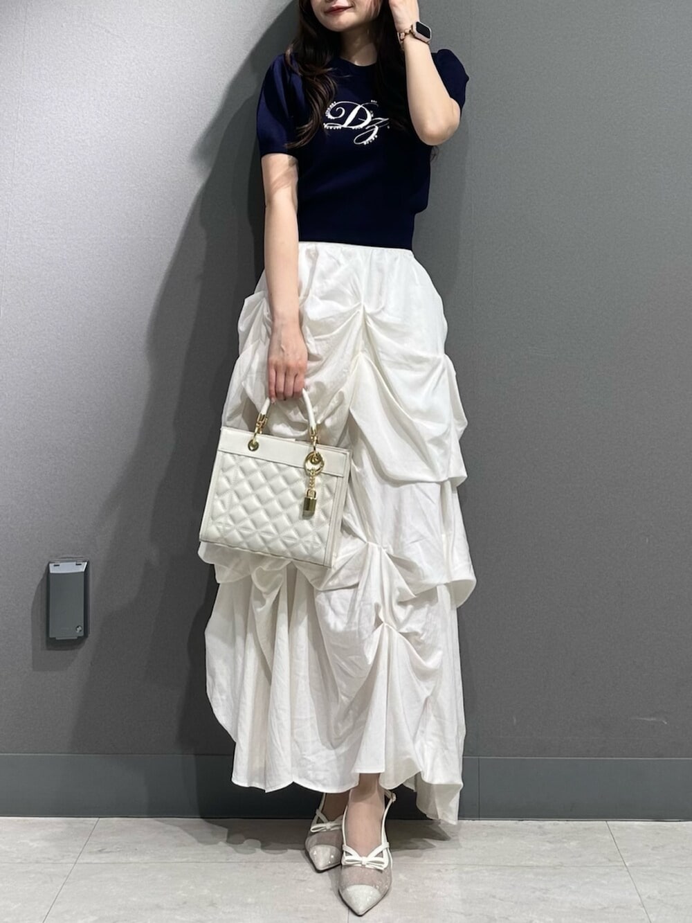 ホワイト系のパンプス、ブルー系のニット/セーター、ホワイト系のスカートを着用したレディースの春コーディネートの2枚目の写真