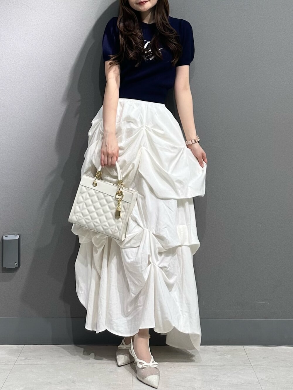 ホワイト系のパンプス、ブルー系のニット/セーター、ホワイト系のスカートを着用したレディースの春コーディネートの5枚目の写真