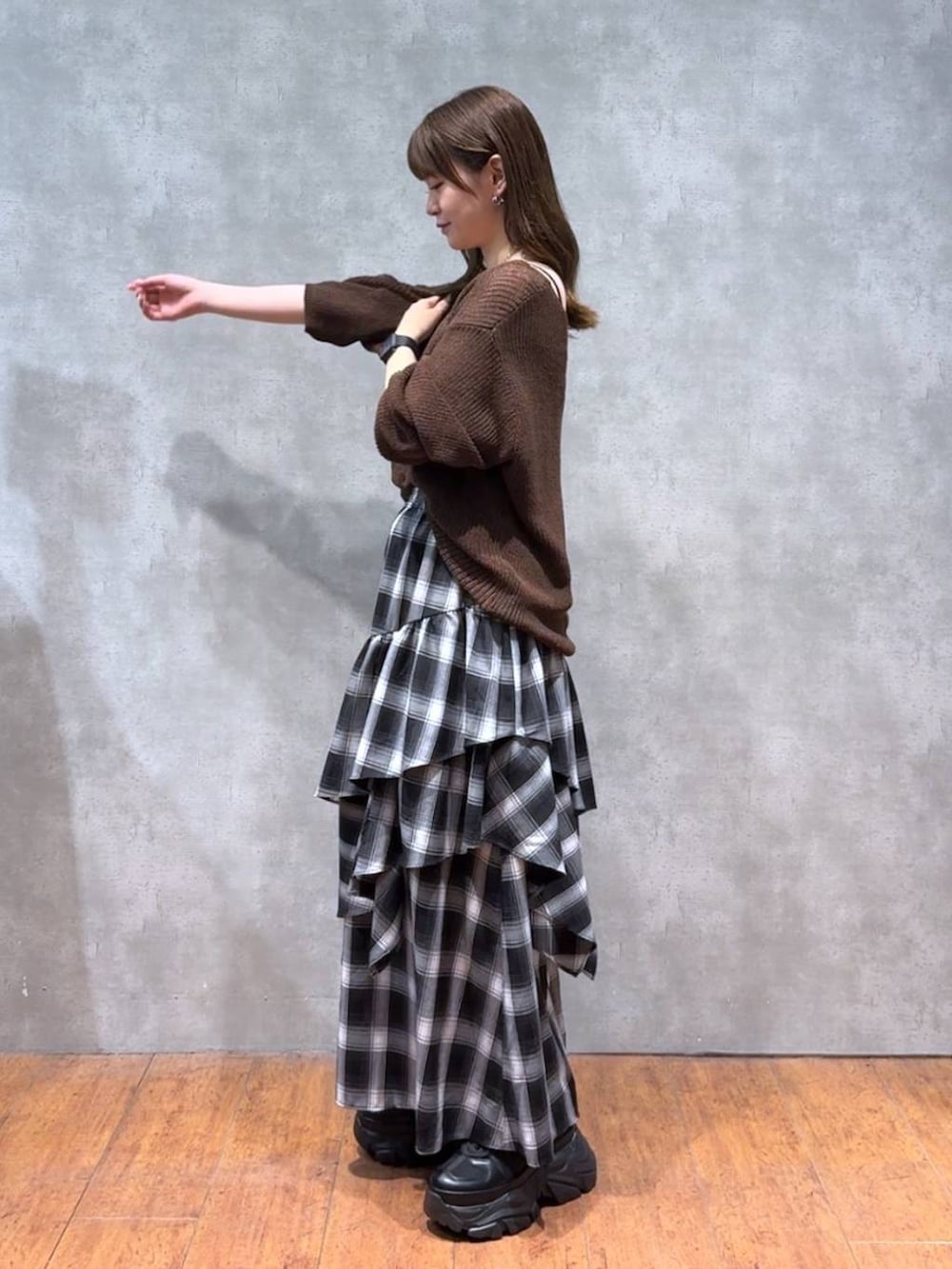 ブラック系のスニーカー、ブラウン系のニット/セーター、ホワイト系のスカートを着用したレディースの秋コーディネートの3枚目の写真