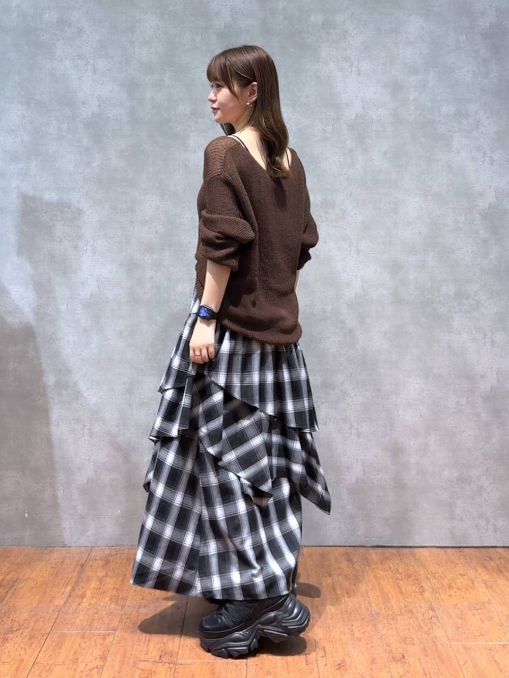 ブラック系のスニーカー、ブラウン系のニット/セーター、ホワイト系のスカートを着用したレディースの秋コーディネートの2枚目の写真