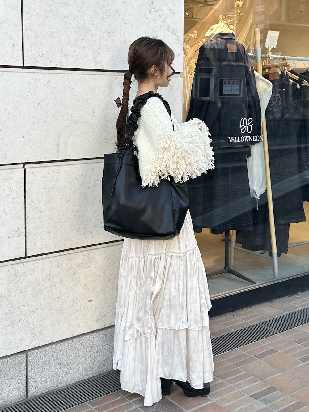 ブラック系のトートバッグ、ブラック系のブーツ、ホワイト系のスカートを着用したレディースの冬コーディネートの2枚目の写真
