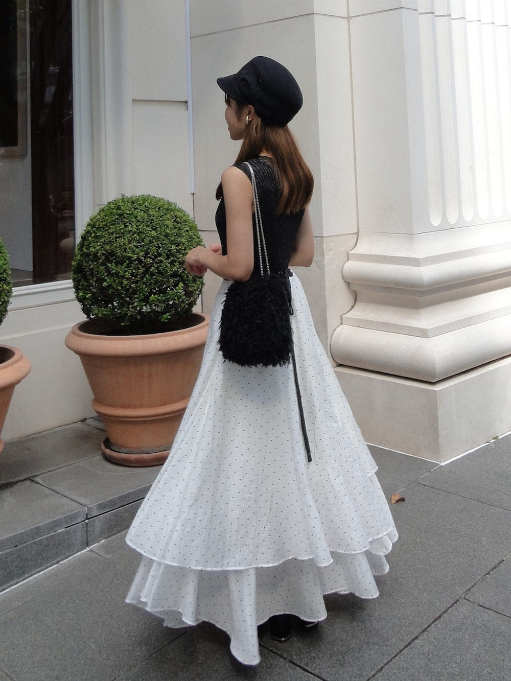 ホワイト系のワンピース、ブラック系のハンドバッグ、ブラック系のサンダルを着用したレディースの夏コーディネートの2枚目の写真