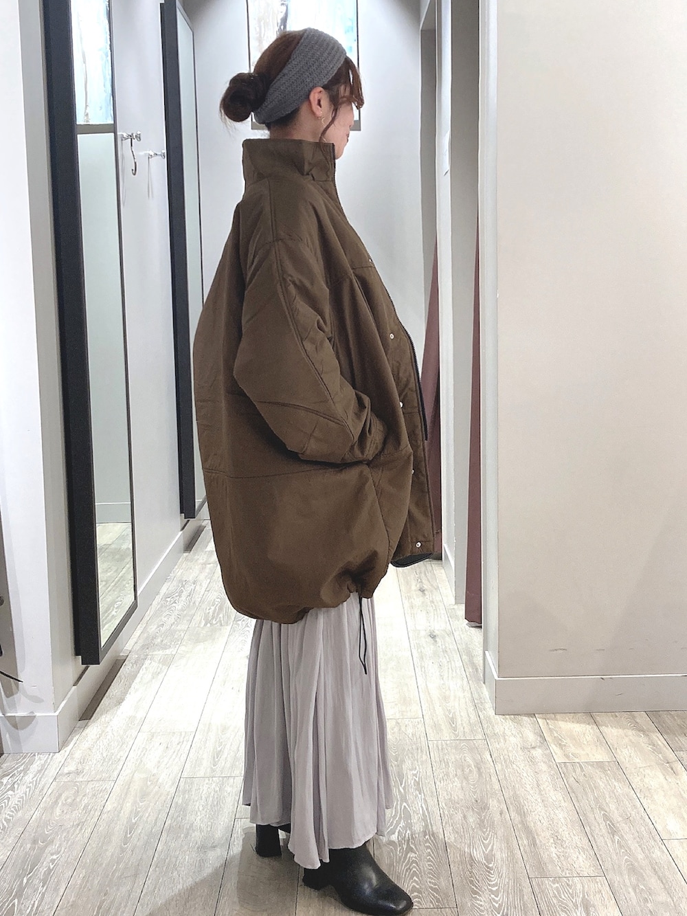 ブラウン系のダウンジャケット/コート、グレー系のスカート、シルバー系のネックレスを着用したレディースの冬コーディネートの2枚目の写真