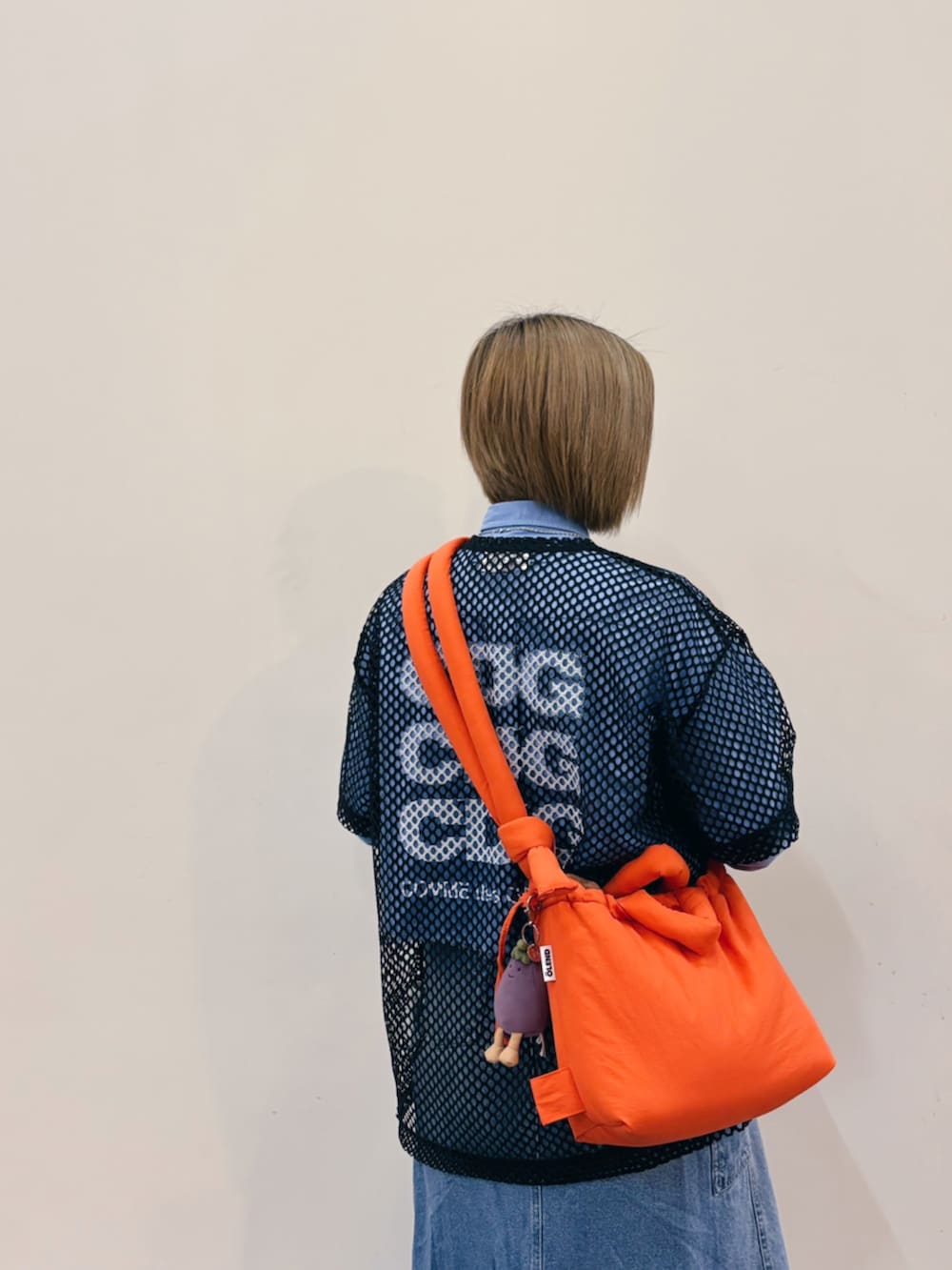 ブラック系のトップス、オレンジ系のショルダーバッグ、ブラック系のスニーカーを着用したレディースの春コーディネートの2枚目の写真