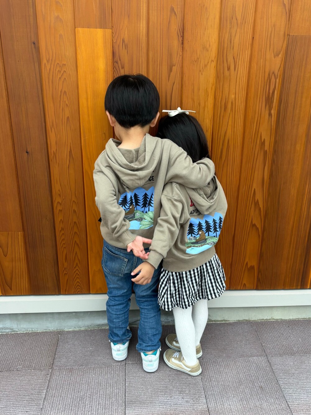 ベージュ系のパーカー、ブルー系のデニムパンツ、ホワイト系のスニーカーを着用したキッズの冬コーディネートの2枚目の写真