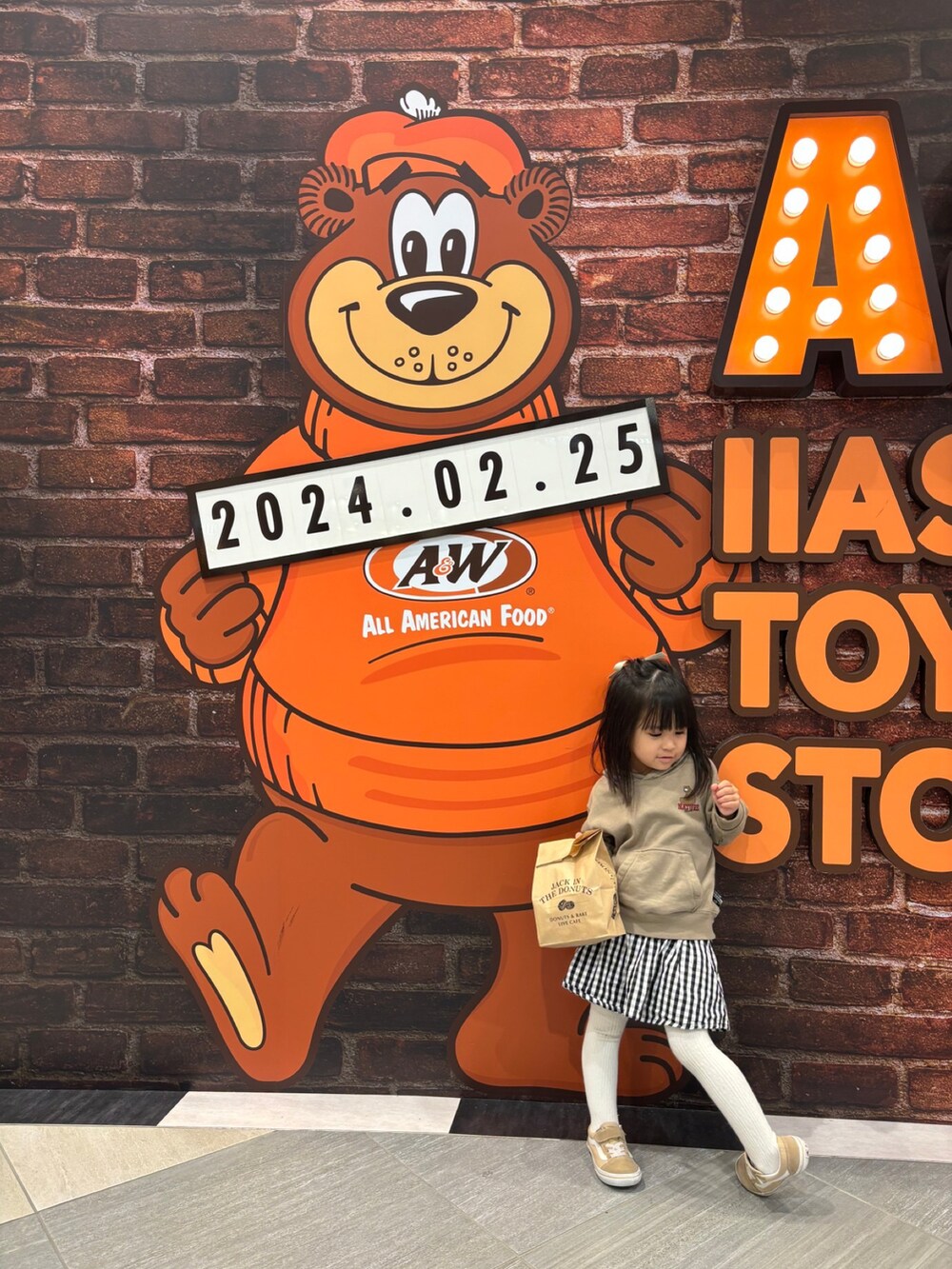 ベージュ系のパーカー、ブルー系のデニムパンツ、ホワイト系のスニーカーを着用したキッズの冬コーディネートの3枚目の写真