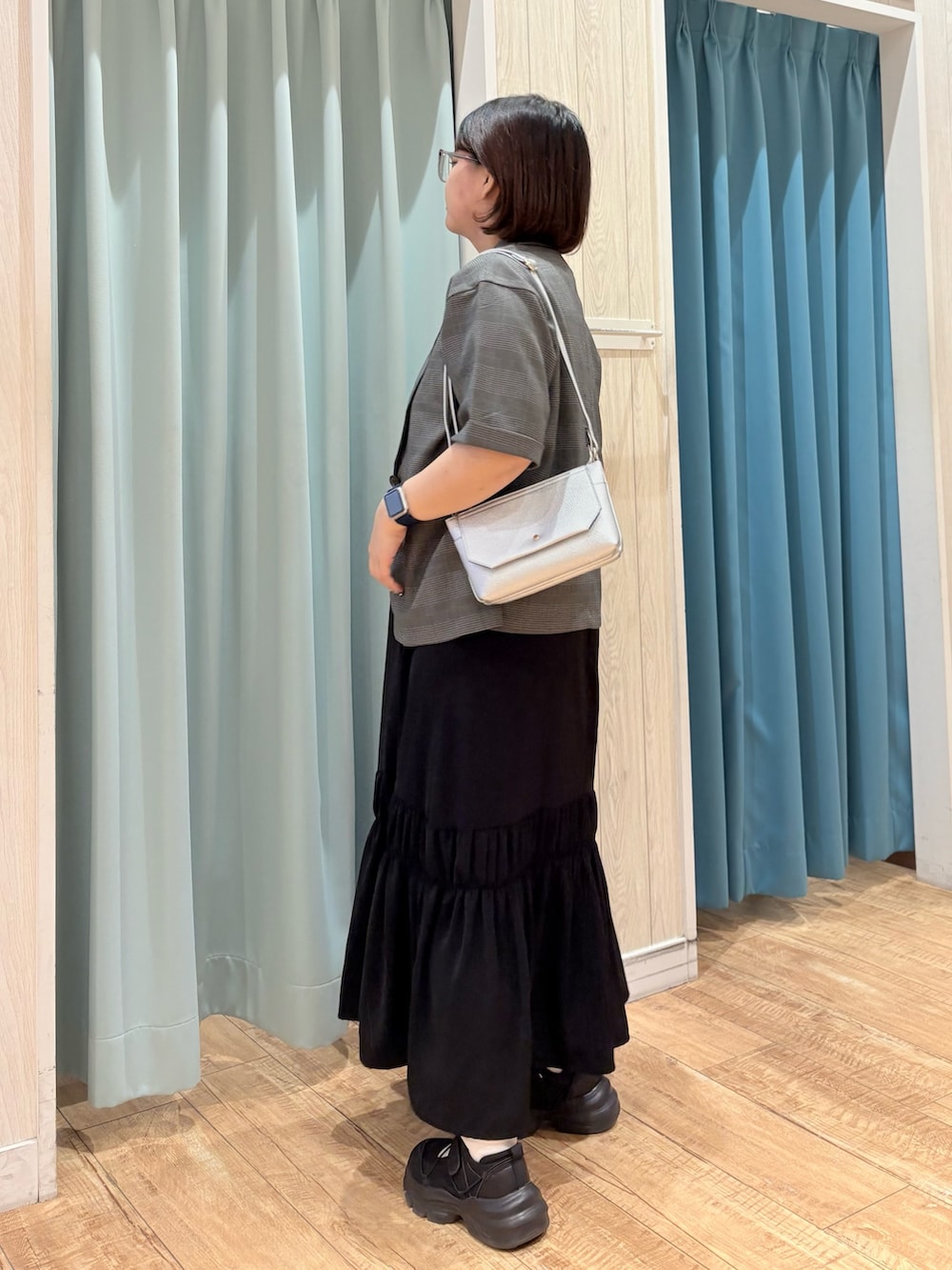 グレー系のテーラードジャケット、ブラック系のワンピース、シルバー系のショルダーバッグを着用したレディースの夏コーディネートの3枚目の写真