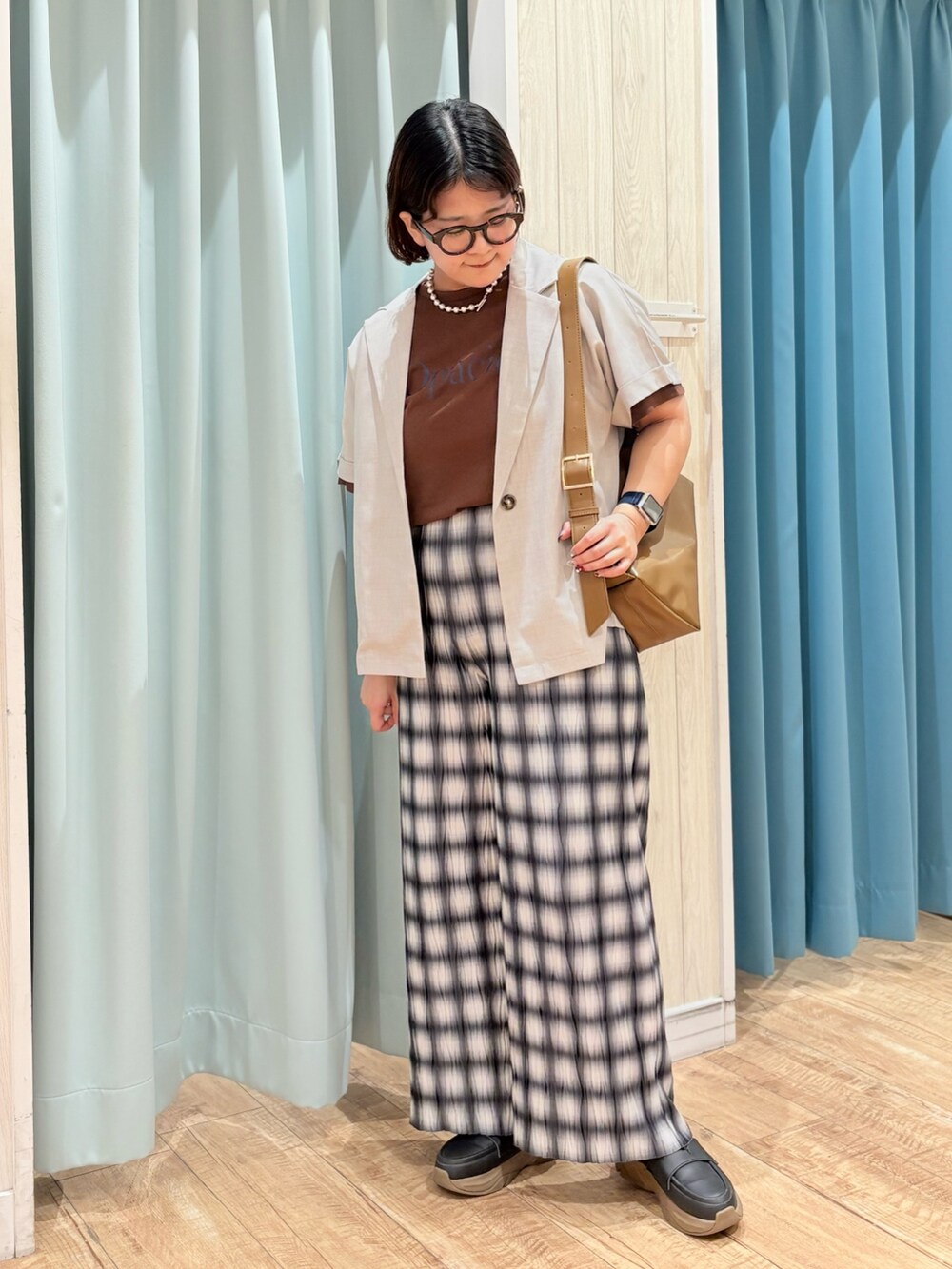 ベージュ系のテーラードジャケット、ブラウン系のTシャツ/カットソー、シルバー系のネックレスを着用したレディースの夏コーディネートの2枚目の写真