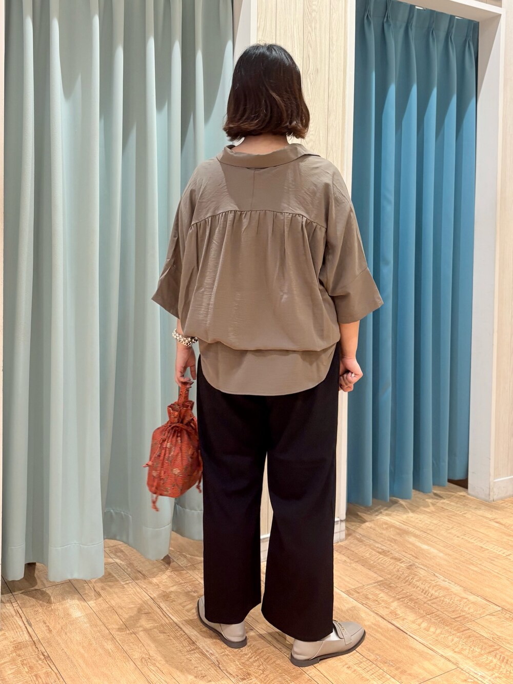 ブラウン系のチュニック、ブラック系のその他パンツ、オレンジ系のショルダーバッグを着用したレディースの秋コーディネートの3枚目の写真