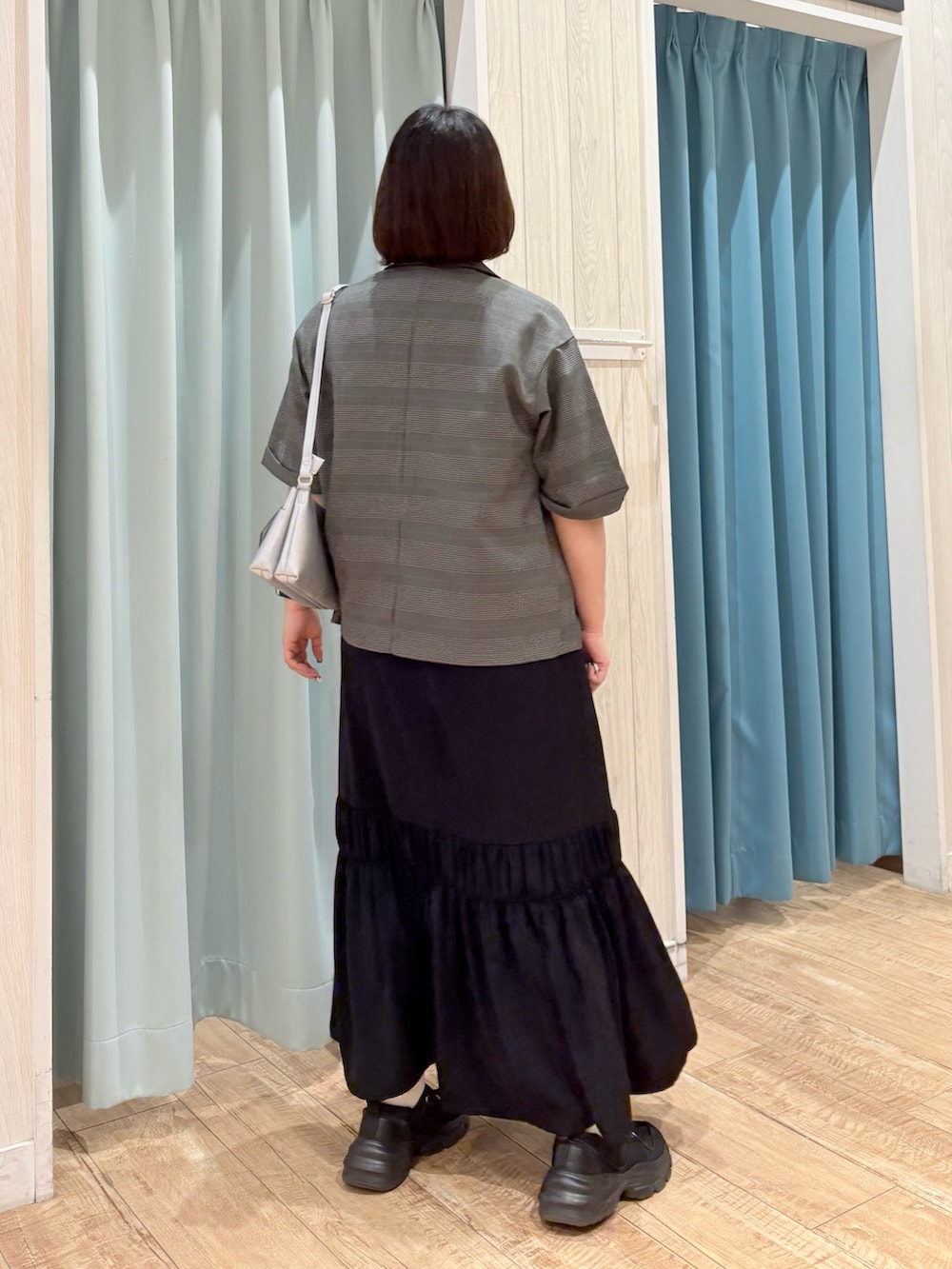 グレー系のテーラードジャケット、ブラック系のワンピース、シルバー系のショルダーバッグを着用したレディースの夏コーディネートの4枚目の写真