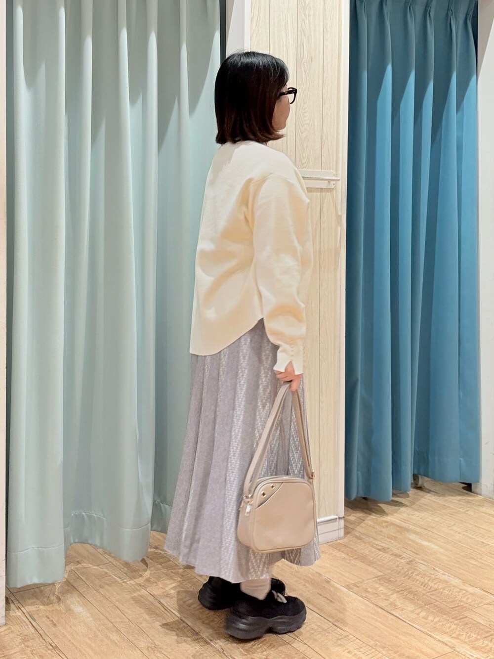 ホワイト系のニット/セーター、グレー系のスカート、ベージュ系のショルダーバッグを着用したレディースの秋コーディネートの3枚目の写真