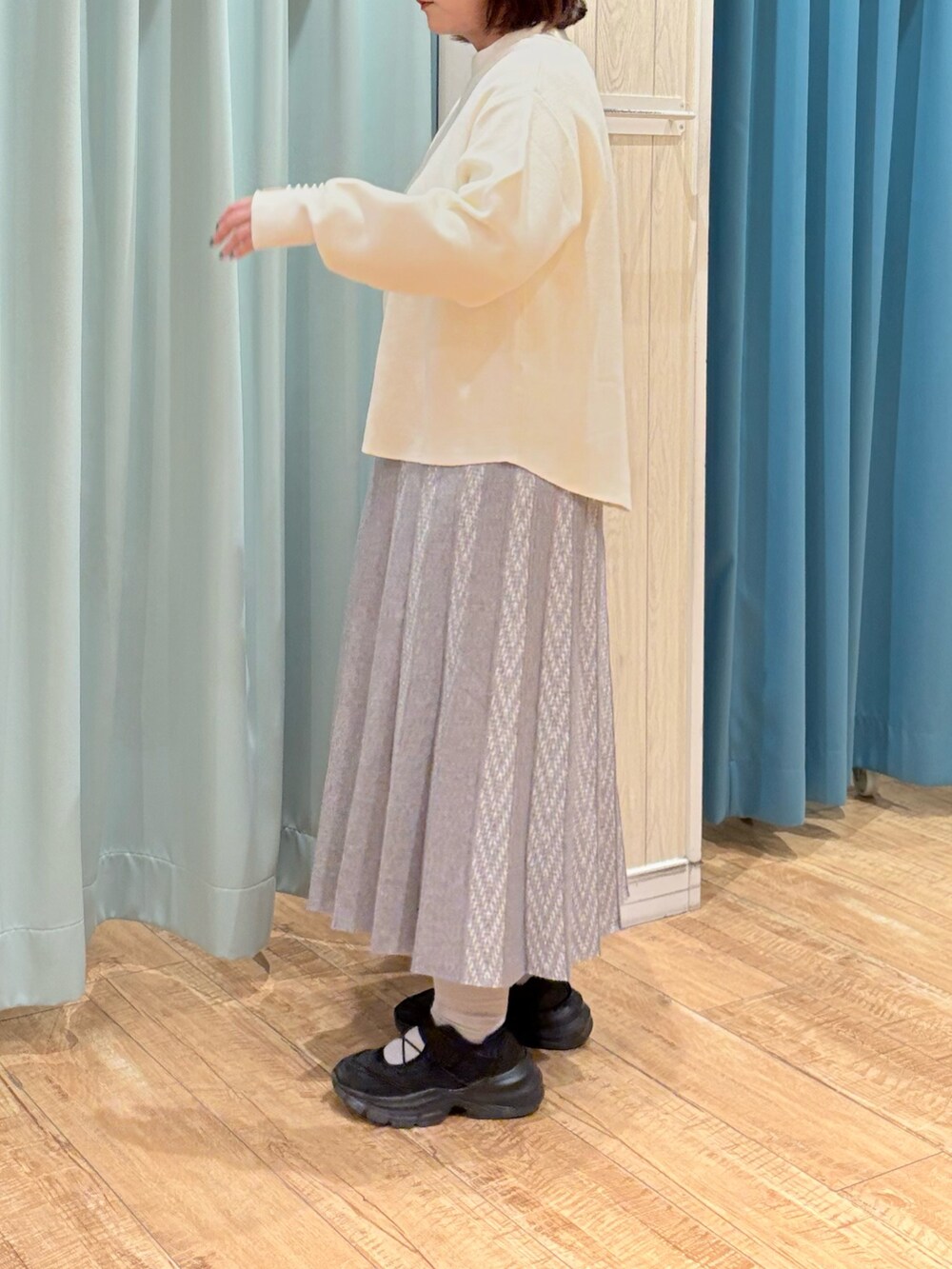 ホワイト系のニット/セーター、グレー系のスカート、ベージュ系のショルダーバッグを着用したレディースの秋コーディネートの5枚目の写真