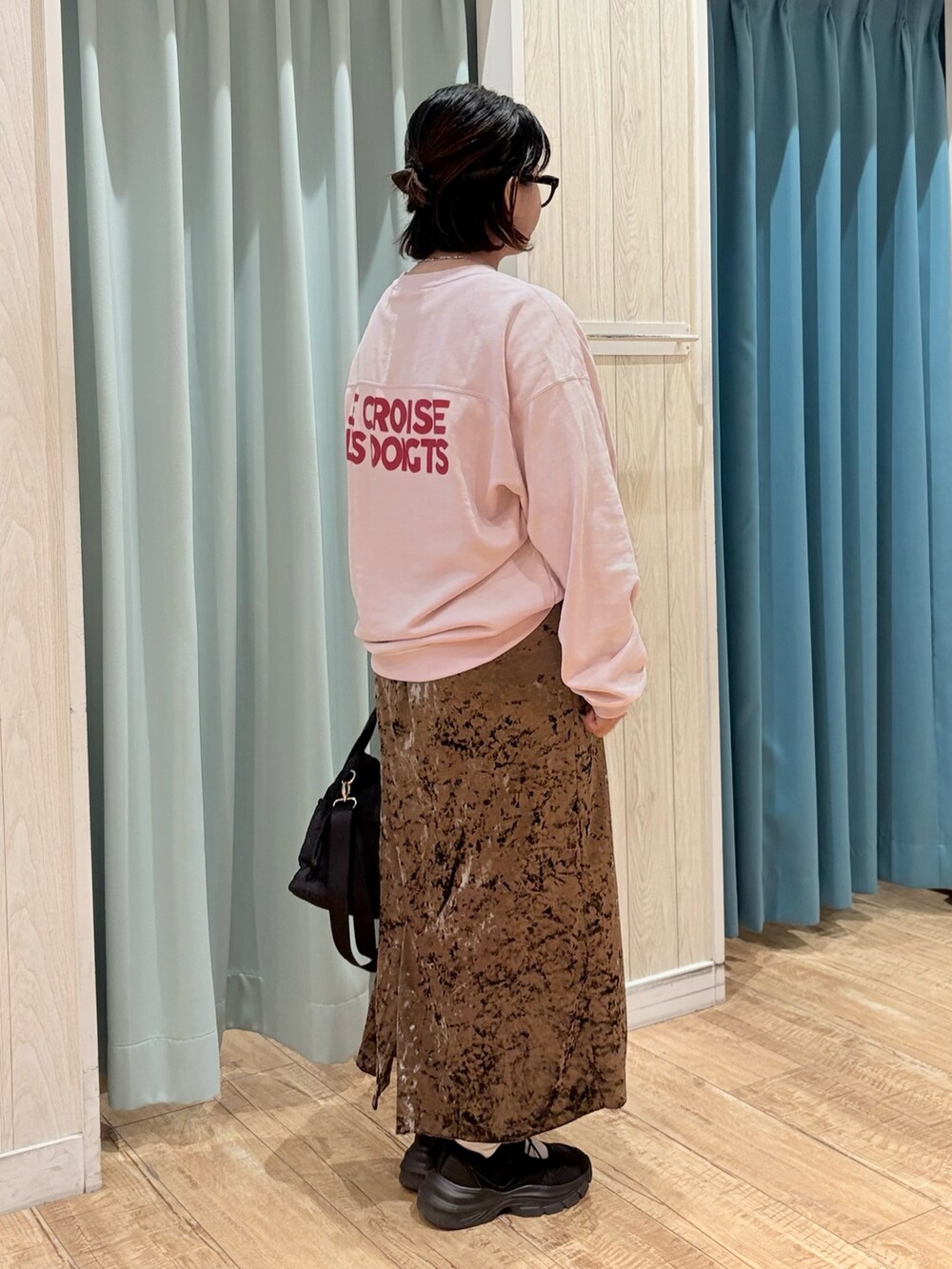 ピンク系のスウェット、ブラウン系のスカート、ブラック系のショルダーバッグを着用したレディースの秋コーディネートの3枚目の写真