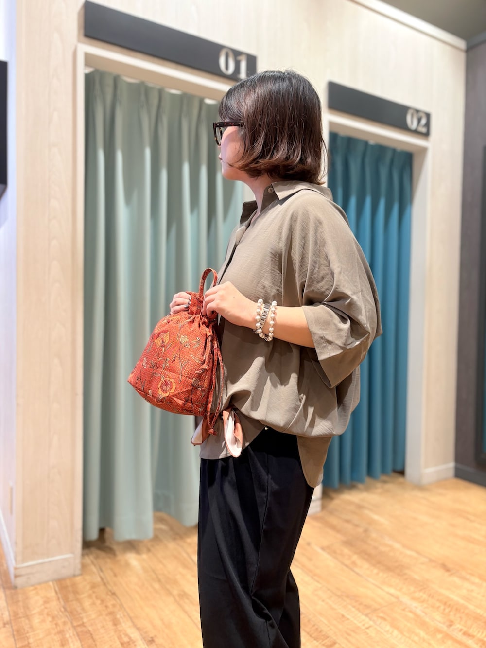 ブラウン系のチュニック、ブラック系のその他パンツ、オレンジ系のショルダーバッグを着用したレディースの秋コーディネートの5枚目の写真