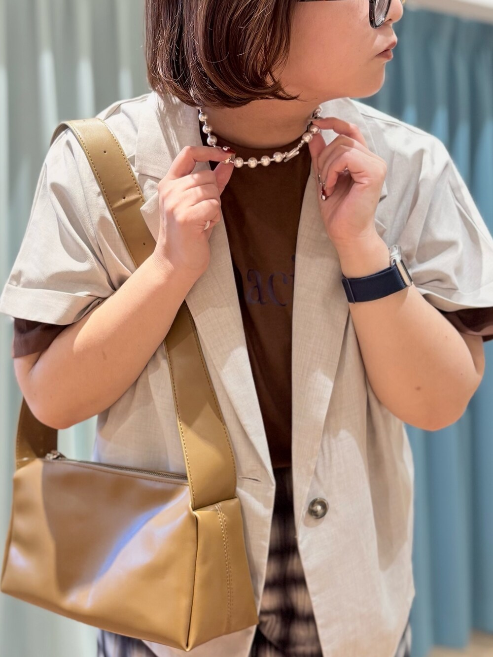 ベージュ系のテーラードジャケット、ブラウン系のTシャツ/カットソー、シルバー系のネックレスを着用したレディースの夏コーディネートの5枚目の写真