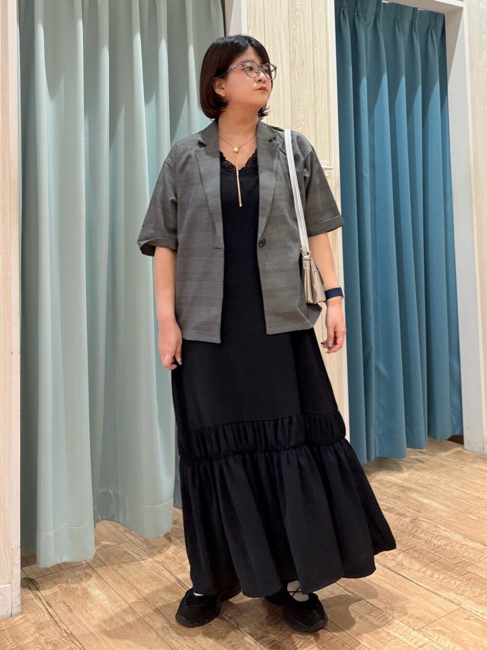 グレー系のテーラードジャケット、ブラック系のワンピース、シルバー系のショルダーバッグを着用したレディースの夏コーディネートの2枚目の写真