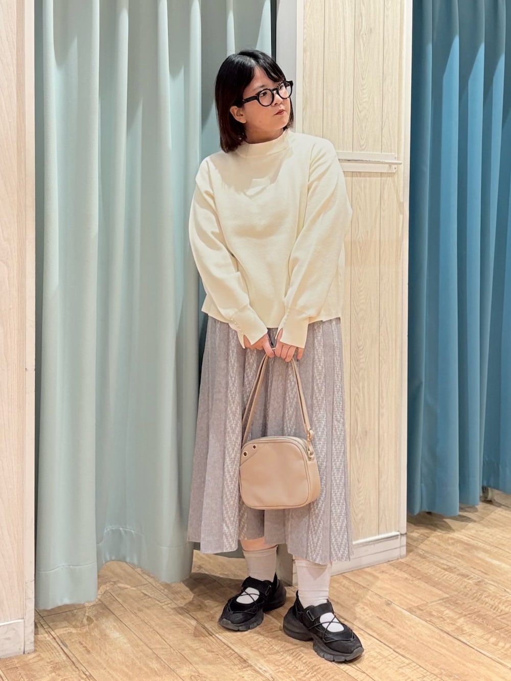 ホワイト系のニット/セーター、グレー系のスカート、ベージュ系のショルダーバッグを着用したレディースの秋コーディネートの2枚目の写真