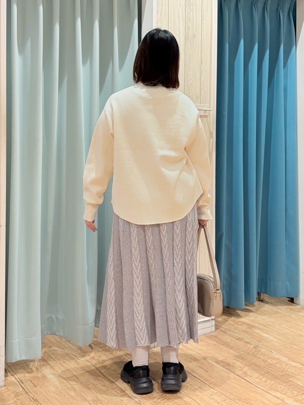 ホワイト系のニット/セーター、グレー系のスカート、ベージュ系のショルダーバッグを着用したレディースの秋コーディネートの4枚目の写真