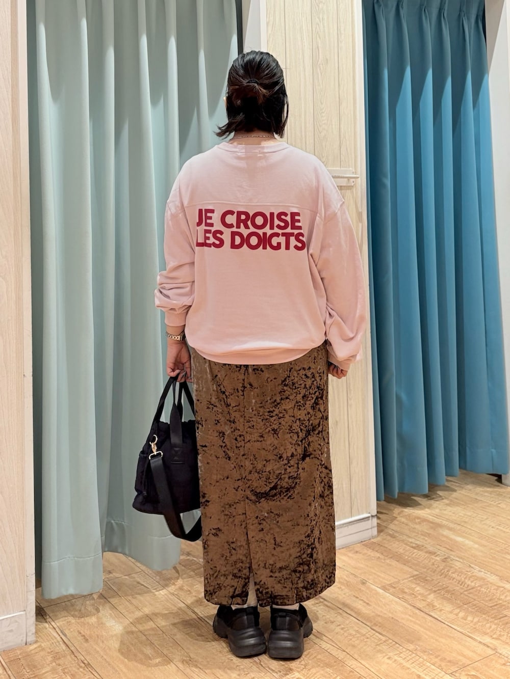 ピンク系のスウェット、ブラウン系のスカート、ブラック系のショルダーバッグを着用したレディースの秋コーディネートの4枚目の写真