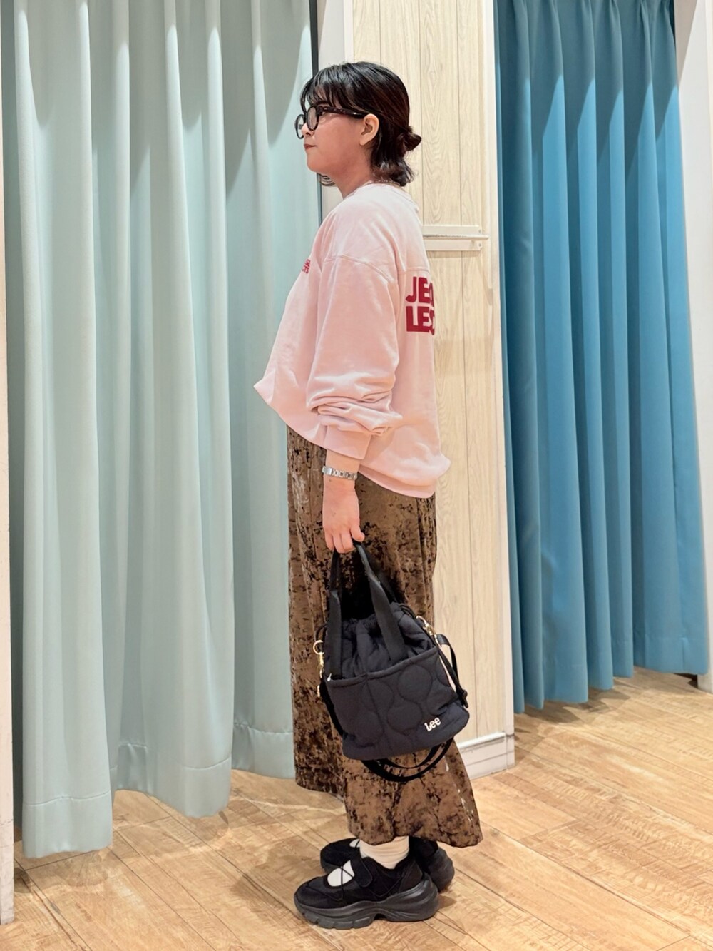 ピンク系のスウェット、ブラウン系のスカート、ブラック系のショルダーバッグを着用したレディースの秋コーディネートの2枚目の写真