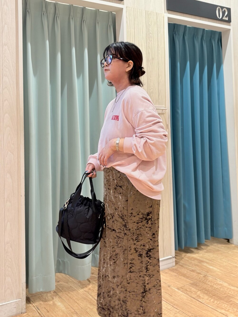 ピンク系のスウェット、ブラウン系のスカート、ブラック系のショルダーバッグを着用したレディースの秋コーディネートの5枚目の写真