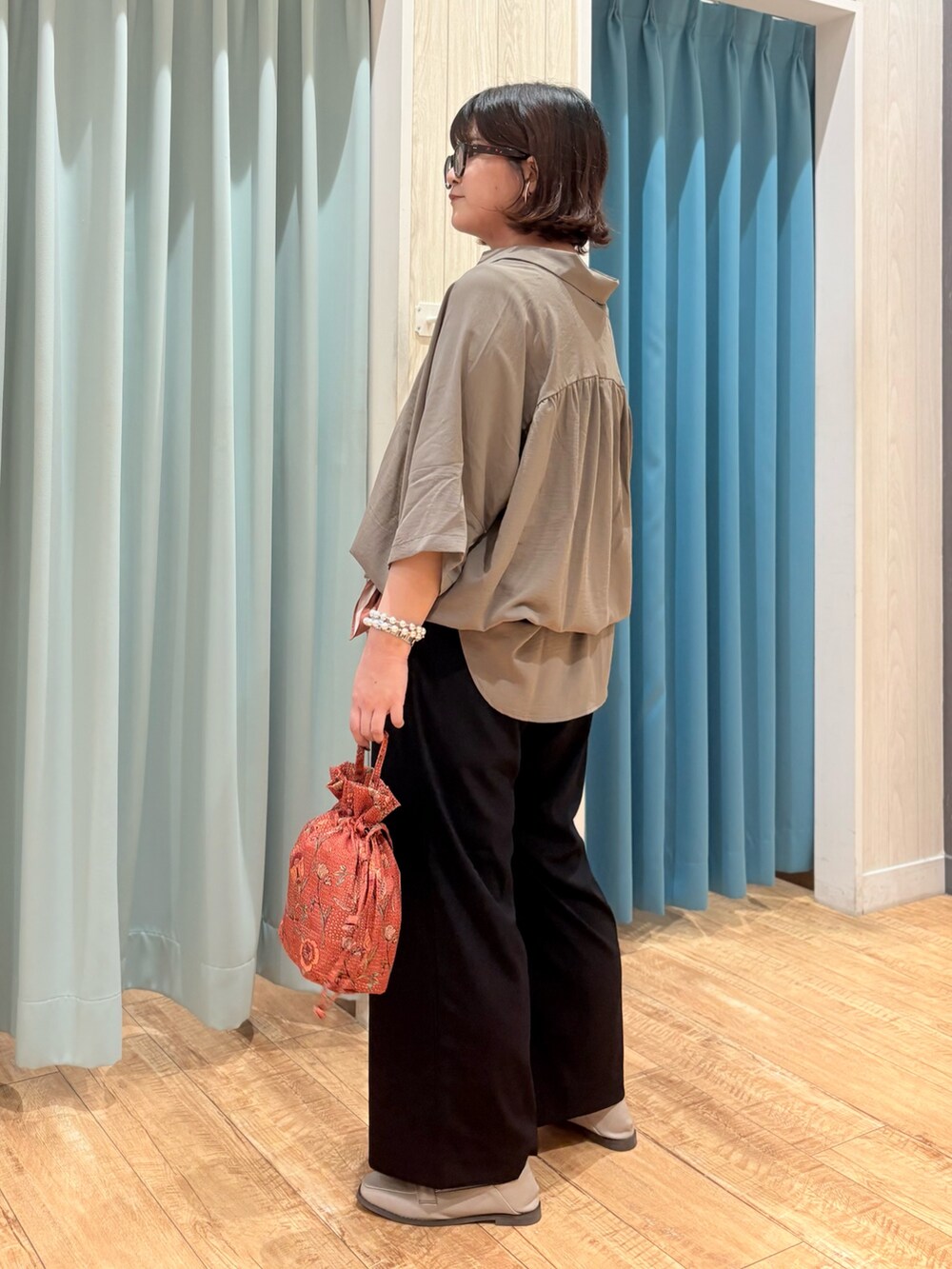 ブラウン系のチュニック、ブラック系のその他パンツ、オレンジ系のショルダーバッグを着用したレディースの秋コーディネートの2枚目の写真