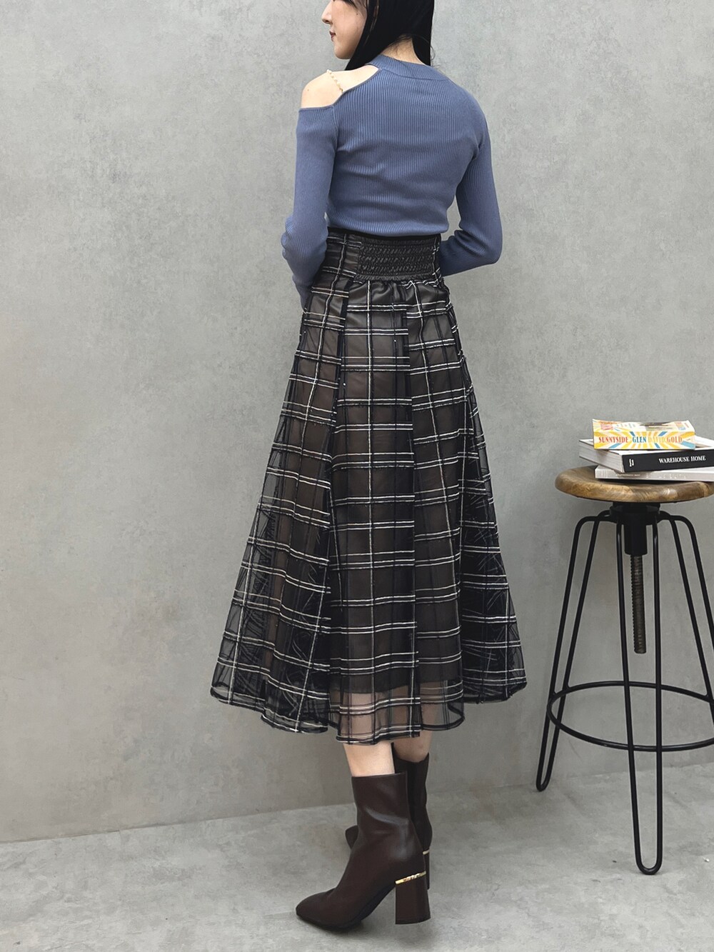ブルー系のニット/セーター、ブラック系のスカート、ブラウン系のブーツを着用したレディースの夏コーディネートの2枚目の写真