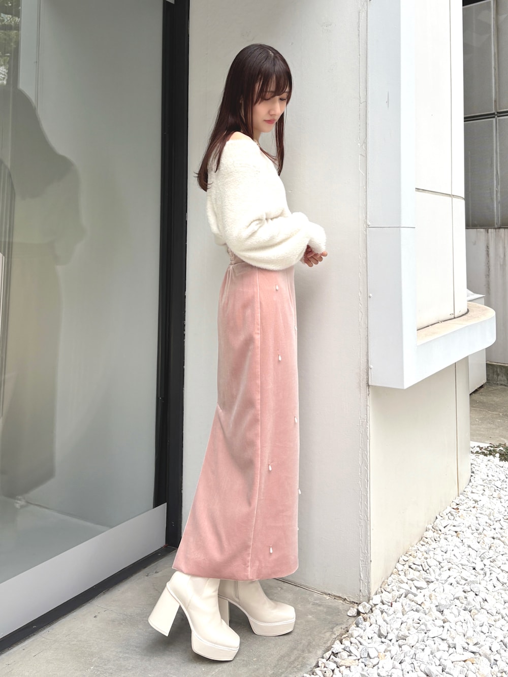 ピンク系のスカート、ホワイト系のニット/セーター、ホワイト系のブーツを着用したレディースの冬コーディネートの2枚目の写真