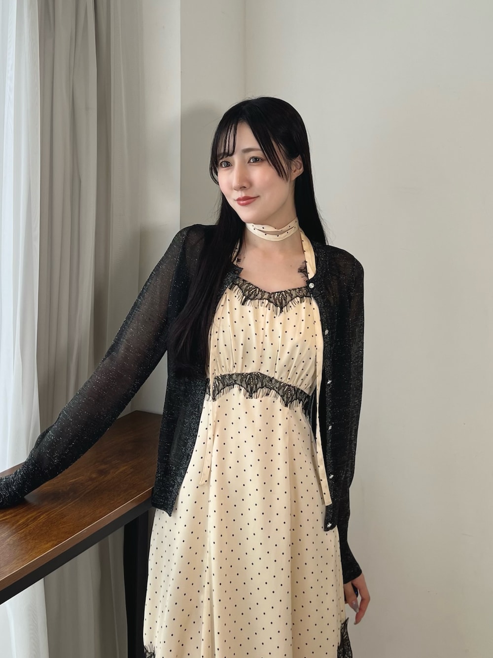ホワイト系のワンピース、ブラック系のカーディガン/ボレロ、ブラック系のブーツを着用したレディースの秋コーディネートの5枚目の写真