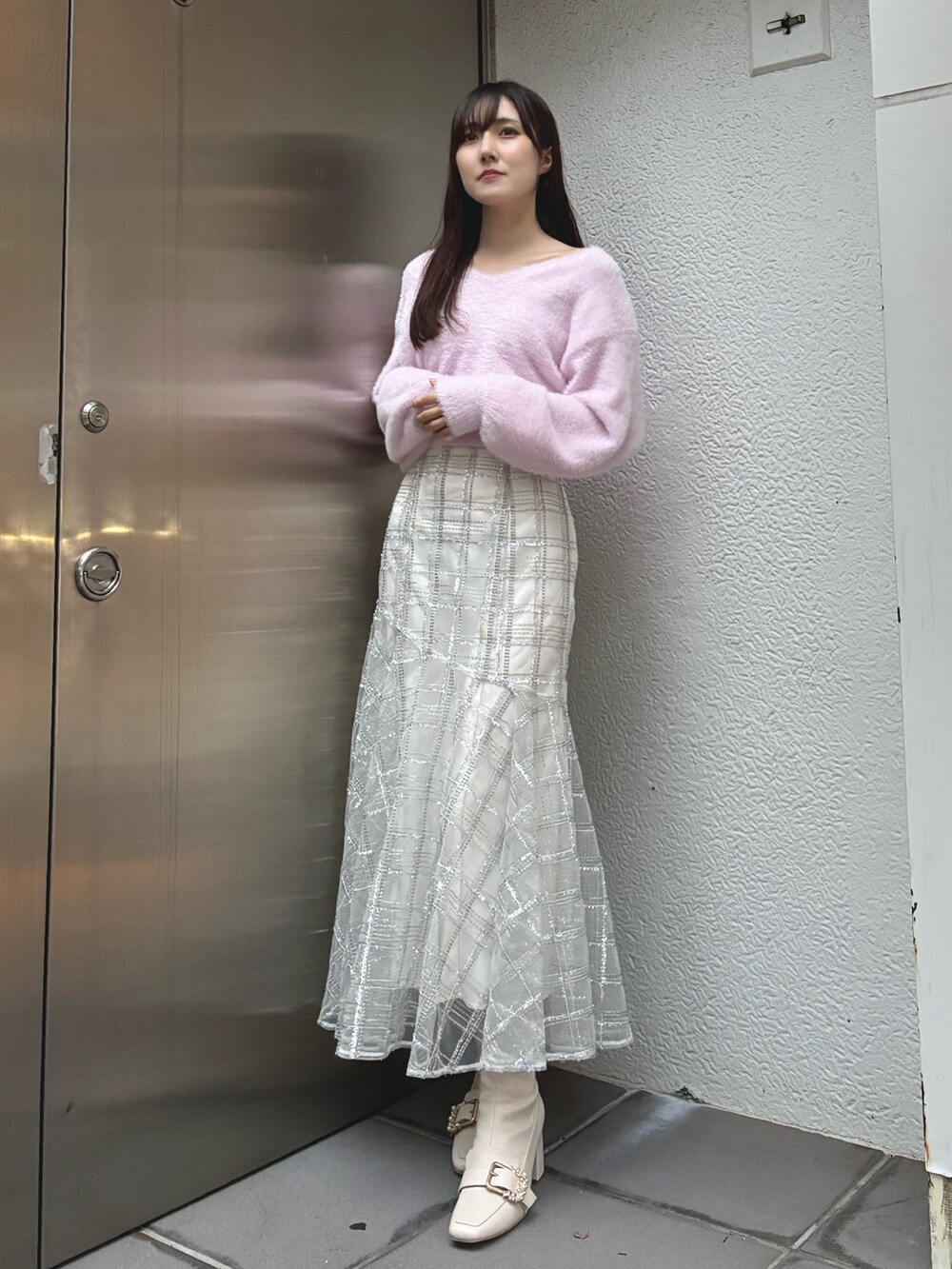ピンク系のニット/セーター、ベージュ系のムートンコート、ホワイト系のスカートを着用したレディースの冬コーディネートの3枚目の写真