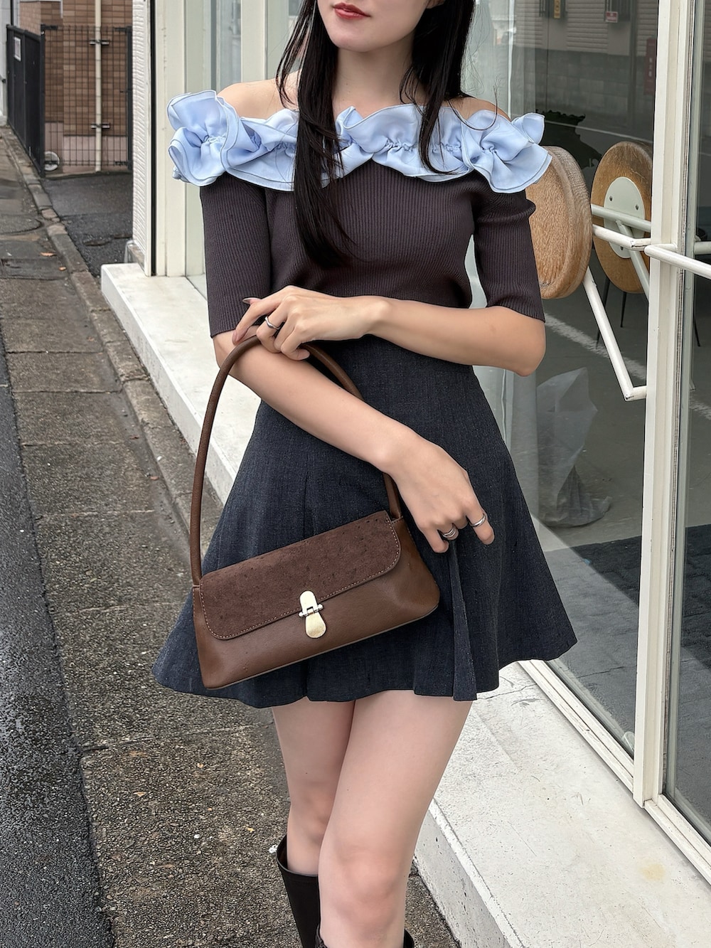 グレー系のニット/セーター、グレー系のスカート、ブラウン系のハンドバッグを着用したレディースの冬コーディネートの4枚目の写真