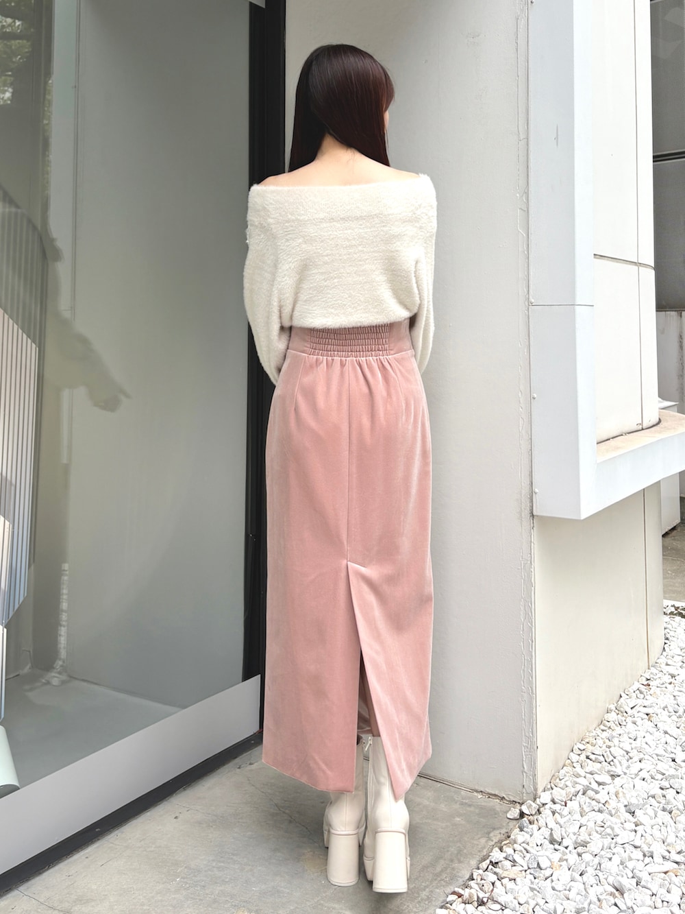 ピンク系のスカート、ホワイト系のニット/セーター、ホワイト系のブーツを着用したレディースの冬コーディネートの3枚目の写真