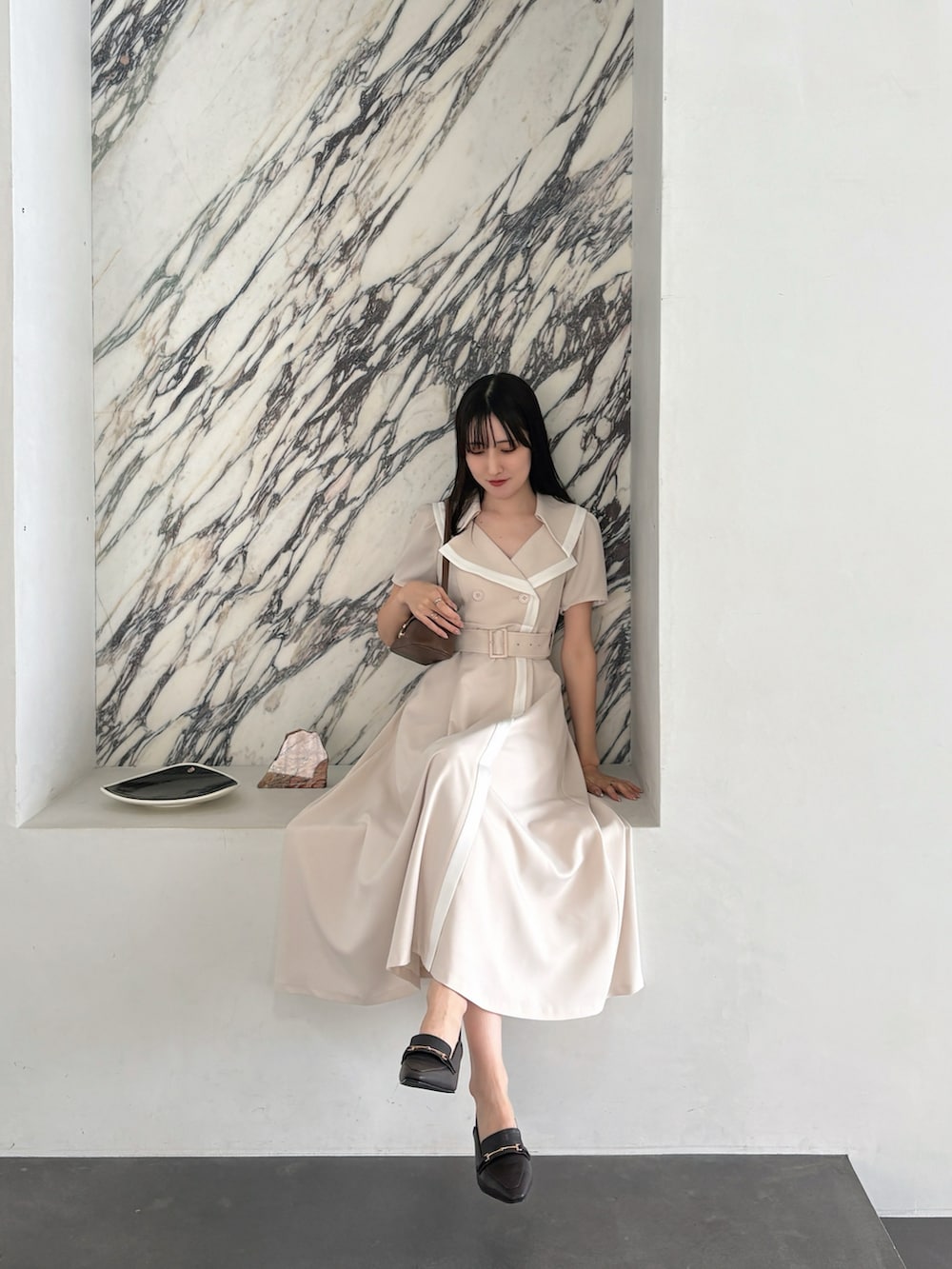 ベージュ系のワンピース、ブラウン系のハンドバッグ、ブラウン系のパンプスを着用したレディースの春コーディネートの4枚目の写真