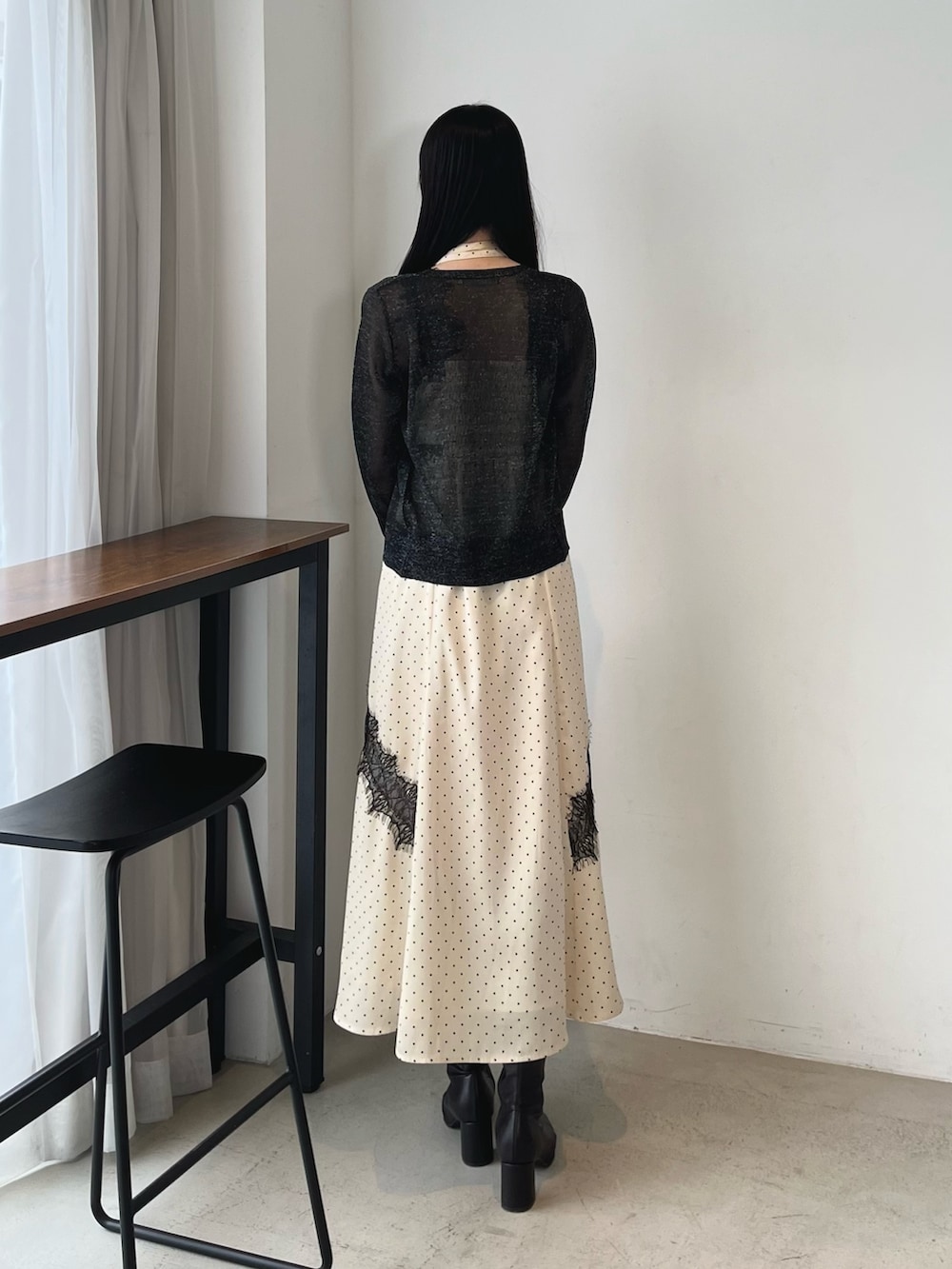ホワイト系のワンピース、ブラック系のカーディガン/ボレロ、ブラック系のブーツを着用したレディースの秋コーディネートの4枚目の写真