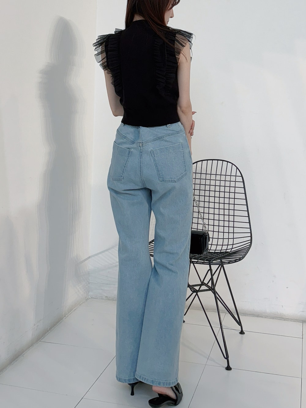 ブラック系のニット/セーター、ブルー系のデニムパンツ、ブラック系のボディバッグ/ウエストポーチを着用したレディースの春コーディネートの3枚目の写真