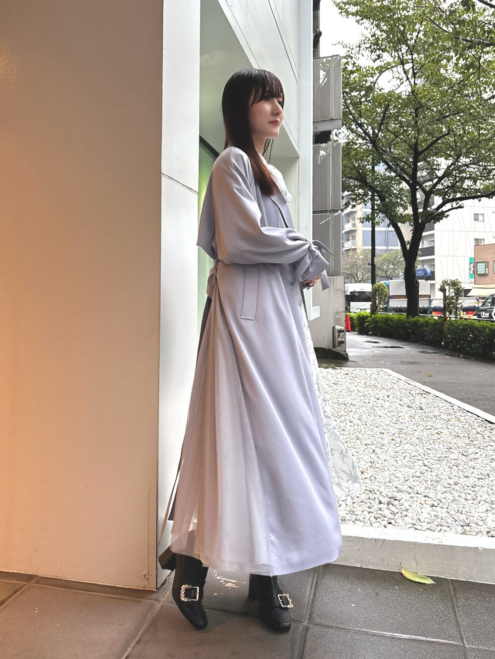 ホワイト系のワンピース、ブルー系のトレンチコート、ブラック系のブーツを着用したレディースの秋コーディネートの2枚目の写真