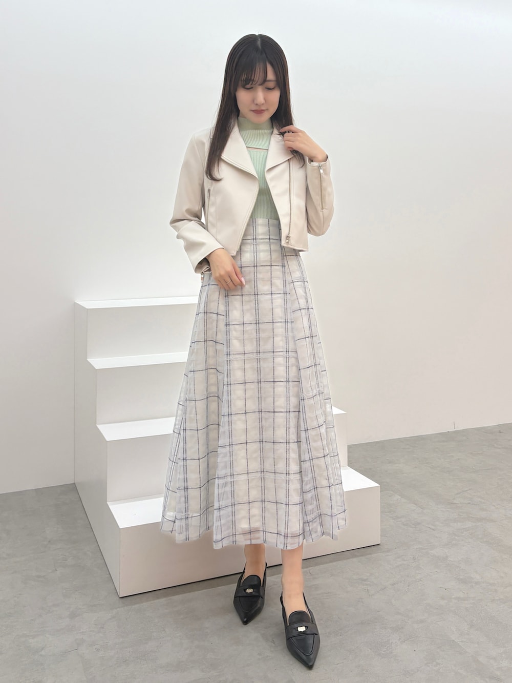 ブルー系のスカート、グリーン系のニット/セーター、ブラック系のパンプスを着用したレディースの夏コーディネートの3枚目の写真