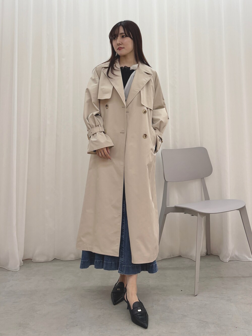 ベージュ系のトレンチコート、ブルー系のスカート、ブラック系のシャツ/ブラウスを着用したレディースの冬コーディネートの2枚目の写真