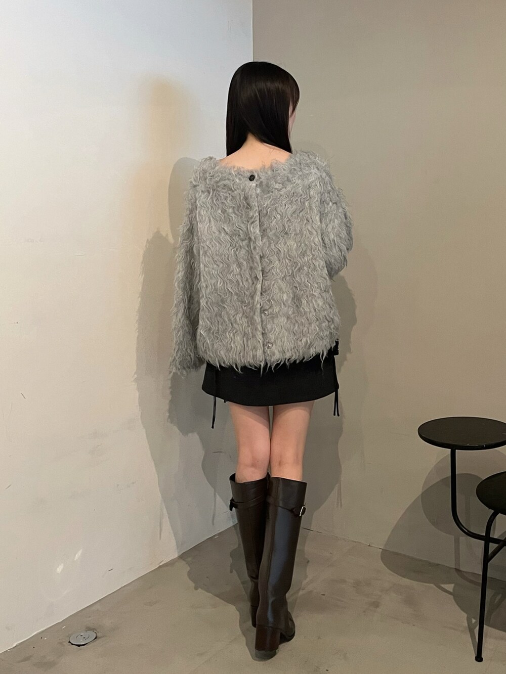 ブラウン系のブーツ、グレー系のニット/セーター、ブラック系のスカートを着用したレディースの秋コーディネートの4枚目の写真