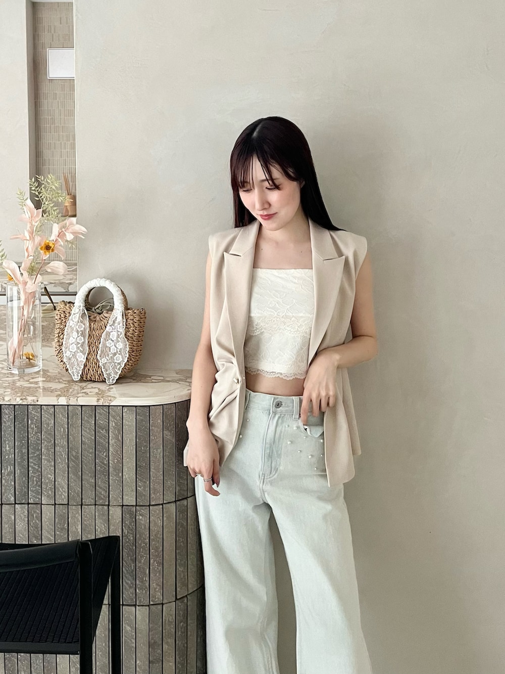 ブラック系のパンプス、ベージュ系のベスト、ブルー系のデニムパンツを着用したレディースの春コーディネートの3枚目の写真