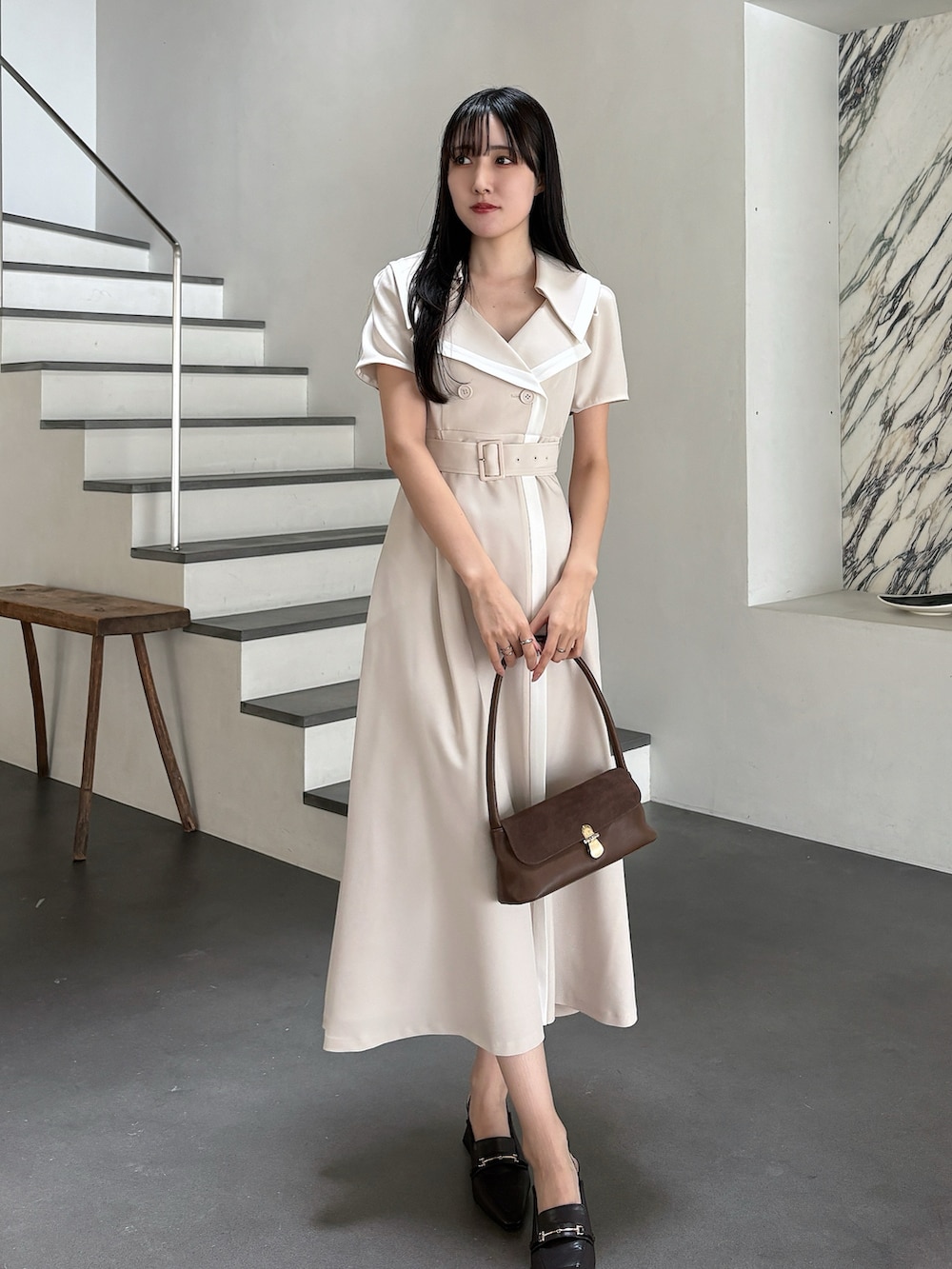 ベージュ系のワンピース、ブラウン系のハンドバッグ、ブラウン系のパンプスを着用したレディースの春コーディネートの2枚目の写真