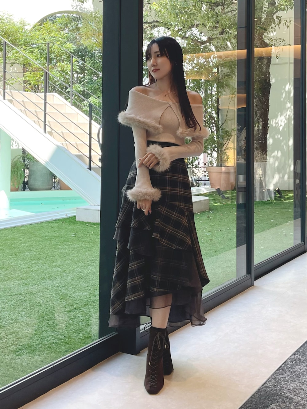 ブラウン系のブーツ、グレー系のスカート、ベージュ系のニット/セーターを着用したレディースの秋コーディネートの2枚目の写真