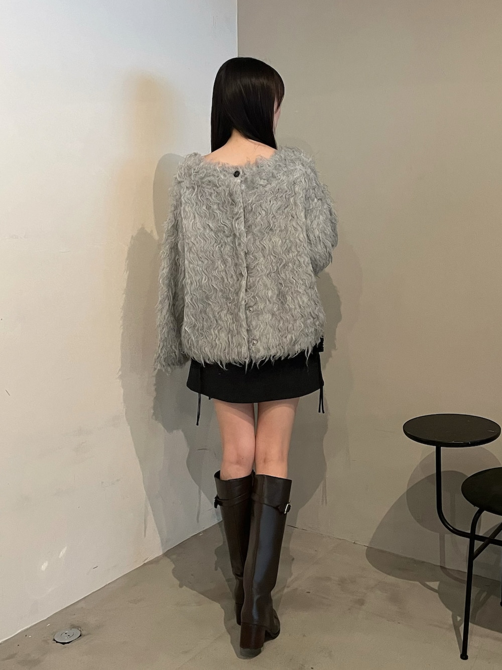 ブラウン系のブーツ、グレー系のニット/セーター、ブラック系のスカートを着用したレディースの冬コーディネートの2枚目の写真