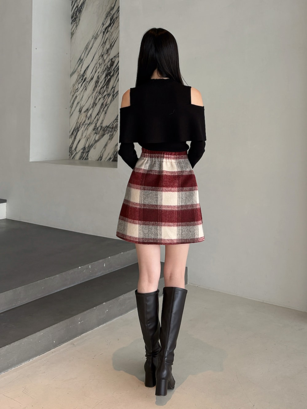 ブラック系のニット/セーター、レッド系のスカート、ブラウン系のブーツを着用したレディースの冬コーディネートの3枚目の写真